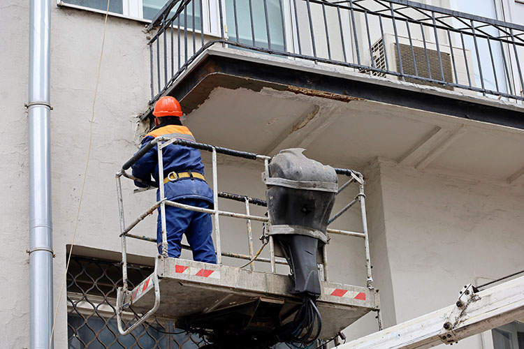 Worker in hydraulic lifting ramp repair the balcony. An sb 326 requirement