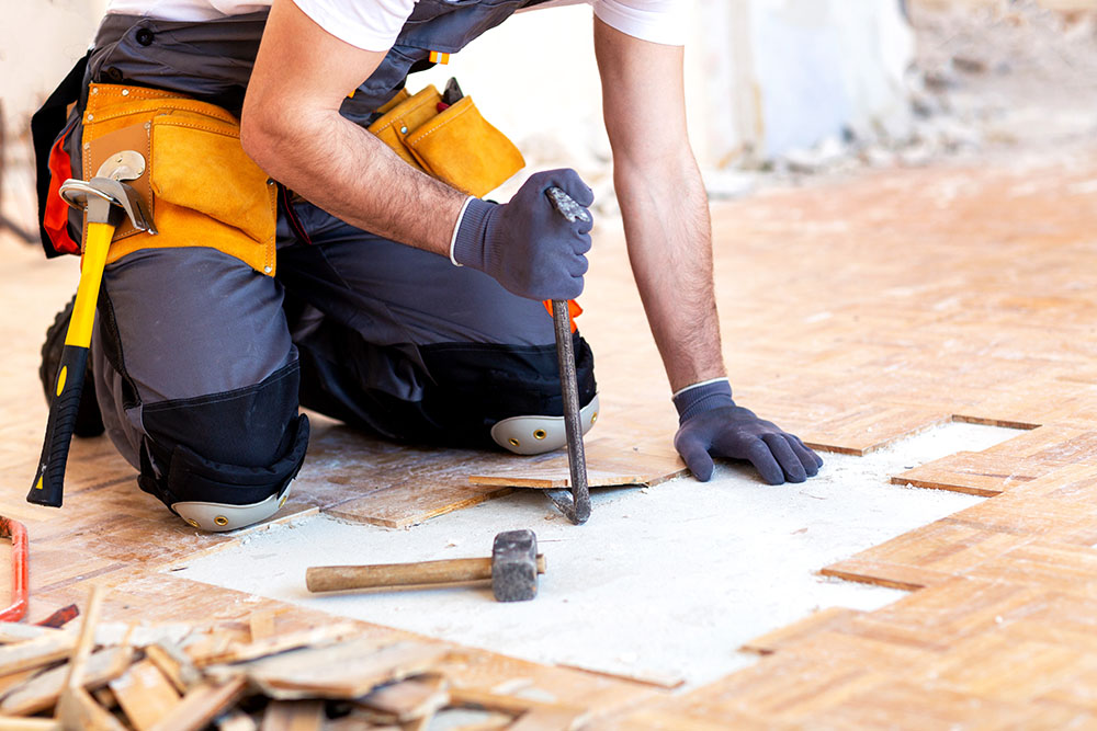 Creative and hard-working handyman in action repairing rotten wood